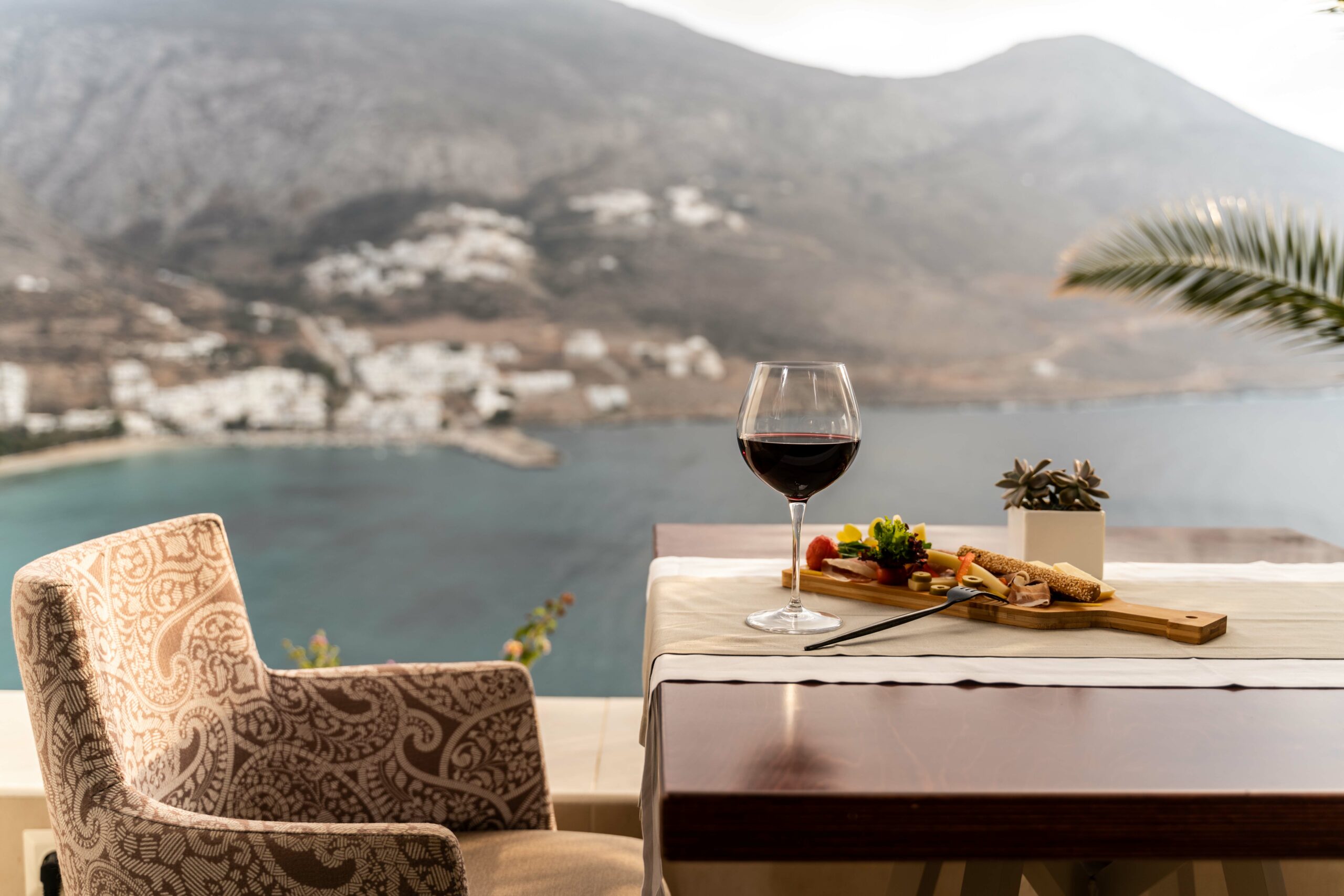 Verre de vin et assiette apéritive sur une terrasse face à la baie